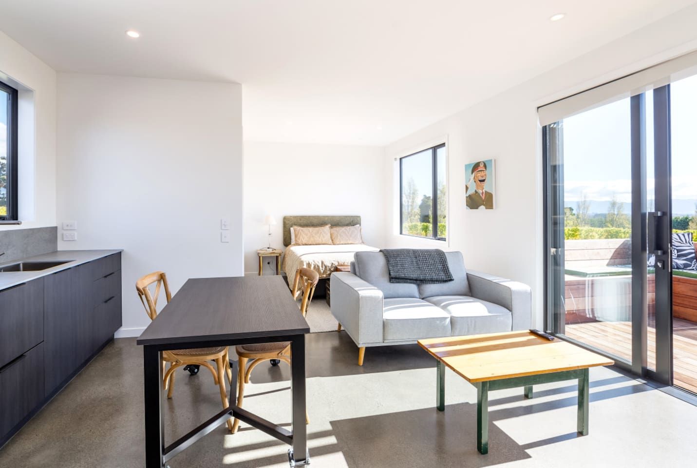 A modern interior with a dining area, sofa, and a view through a glass door.