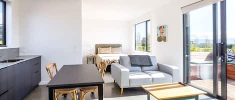 Un intérieur moderne comprenant un coin repas, un canapé et une vue à travers une porte vitrée.