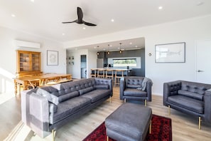 A modern living room with a sectional sofa, two armchairs, and a red patterned rug.