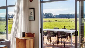 Una habitación con un amplio ventanal corredero que da a un espacio exterior con mesa y sillas.