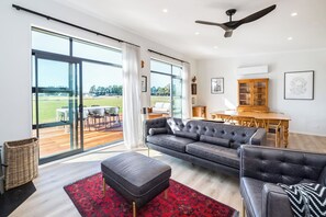 A spacious living room with a large sofa, a coffee table, and a view through floor-to-ceiling windows.