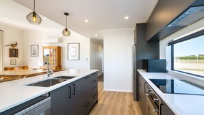 Una cocina moderna con una isla central, electrodomésticos integrados e iluminación colgante.