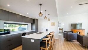 Una cocina moderna con una isla central, taburetes de bar e iluminación colgante.