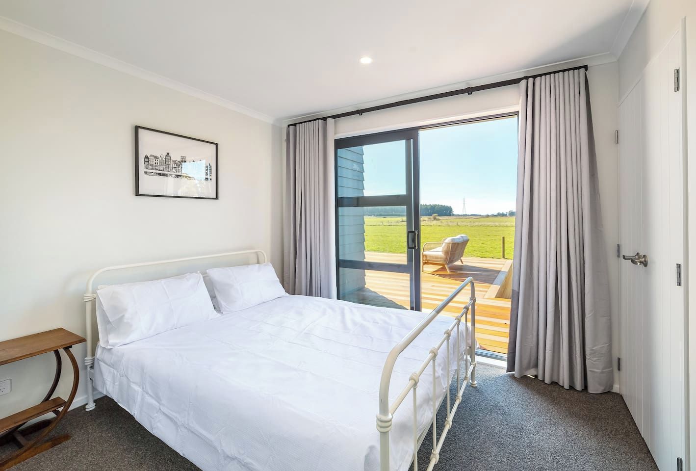 A hotel room with a bed, a chair, a picture on the wall, and a view of the outdoors.