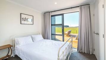 A hotel room with a bed, a chair, a picture on the wall, and a view of the outdoors.