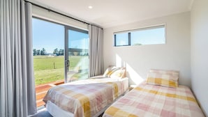 Una habitación de hotel con dos camas, un ventanal corredero a un balcón y una ventana pequeña.