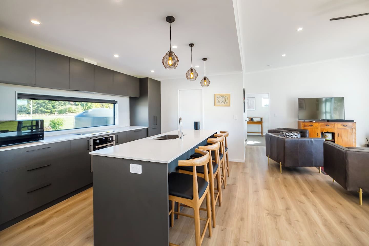 A modern kitchen with a central island, bar stools, and pendant lighting.