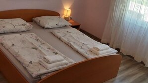 A single bed with a wooden headboard, two pillows, a bedside lamp, and a floral artwork on the wall.