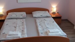 A double bed with floral-patterned bedding, two bedside tables with lamps, and a wall-mounted artwork.