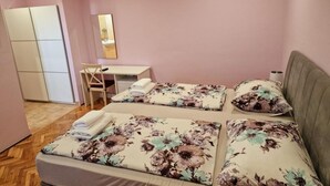 A bedroom with two beds, a desk, a chair, and a wardrobe.