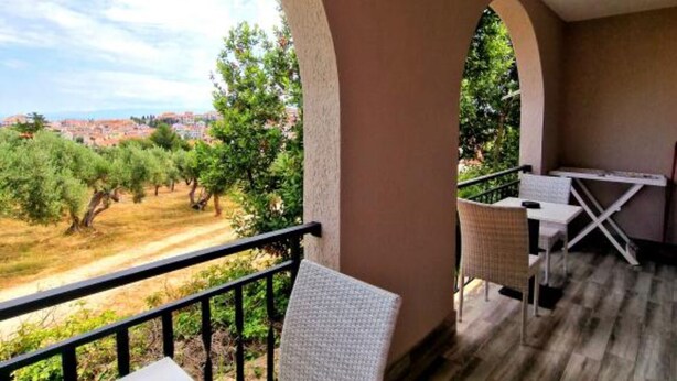 A balcony with a view of olive trees and a distant town.