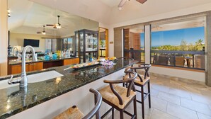 A modern kitchen with a large island, bar stools, and a view of the outdoors.