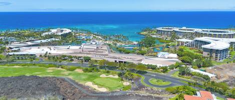 An aerial view of a resort with multiple buildings, a golf course, and a coastline.