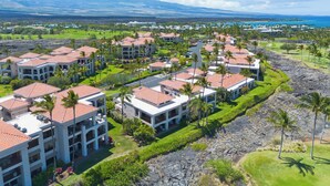 A resort with multiple buildings featuring red-tiled roofs, surrounded by lush greenery and palm trees.