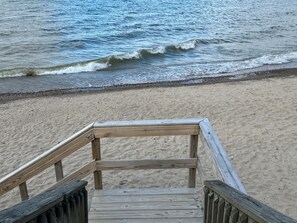 A wooden staircase leading to a sandy beach with ocean waves in the background. - Stones Throw Cottage - Beautiful beach within 2 miles of both major campgrounds (Deckerville)