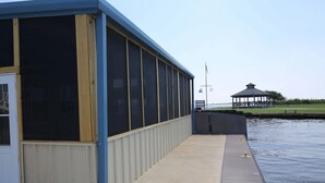 Un bâtiment doté de grandes fenêtres et d’une passerelle couverte, situé au bord d’un plan d’eau.