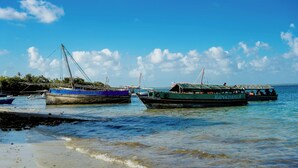 A calm coastal scene with several boats docked at a pier. - Signature Collection by Eight Continents, Mafia Island (Mafia Island)