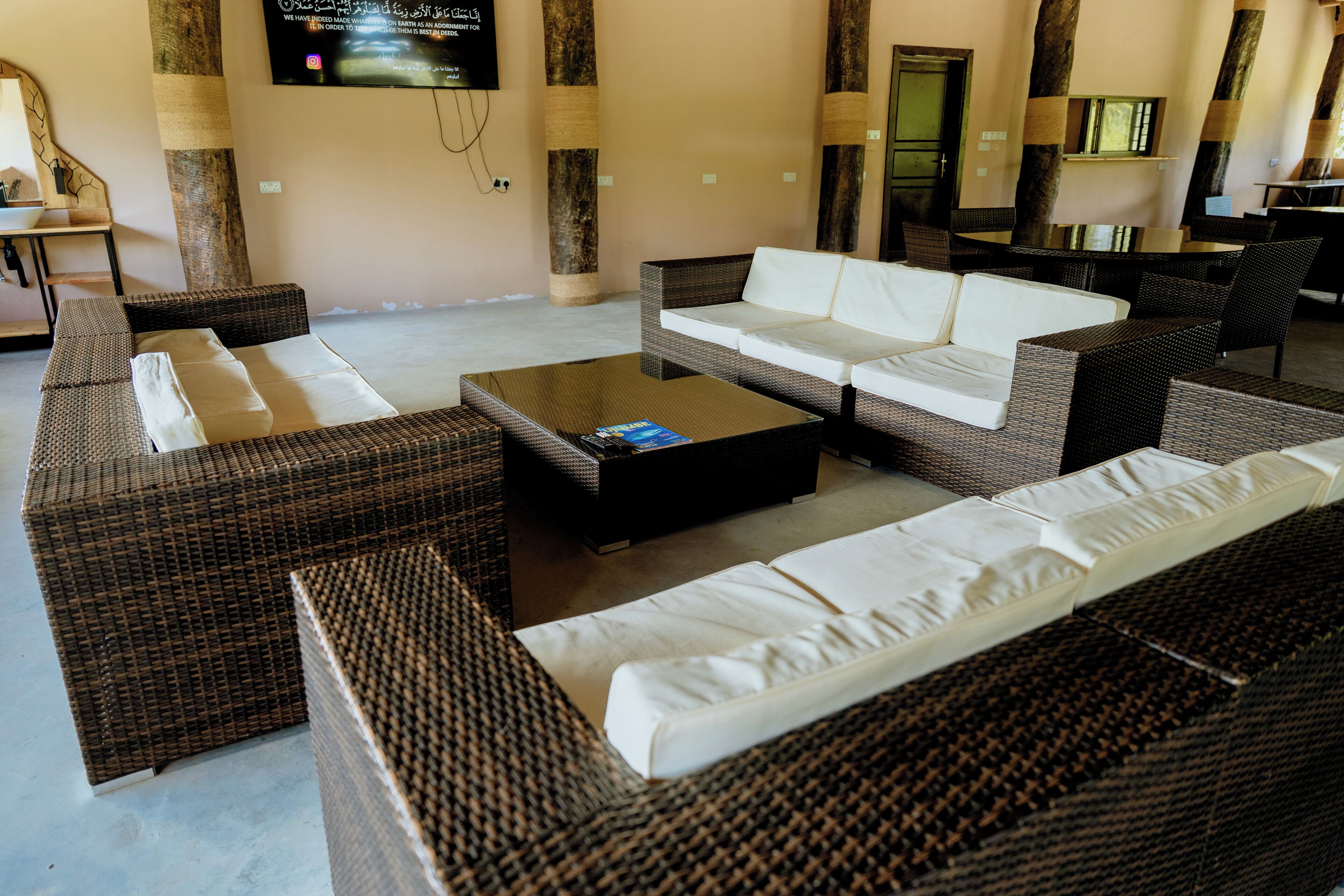 A lounge area with wicker furniture, a flat-screen TV, and a wall-mounted TV.