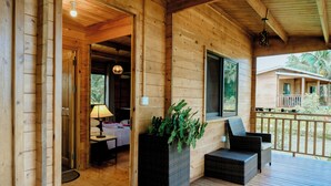 A wooden cabin with a porch, wicker furniture, and a potted plant. - Signature Collection by Eight Continents, Mafia Island (Mafia Island)