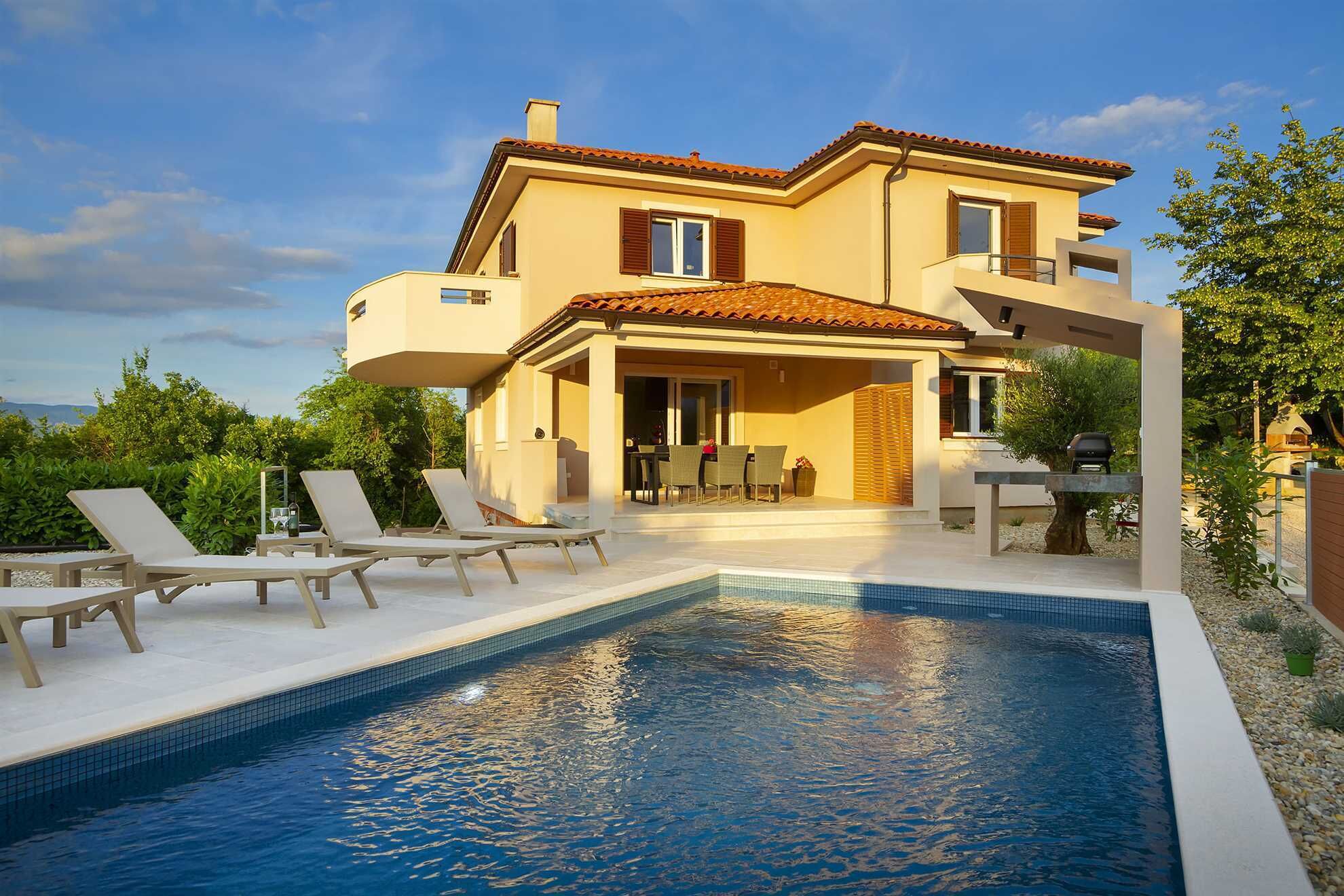 A two-story house with a swimming pool, outdoor seating, and a barbecue area.