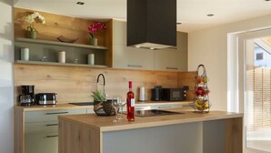 Een moderne keuken met een centraal eiland, houten kastjes en een inbouwmagnetron.