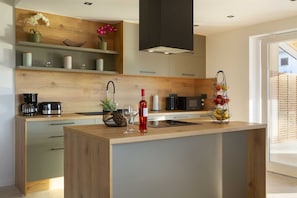 Une cuisine moderne dotée d’un îlot central, de meubles en bois et d’un four à micro-ondes encastré.