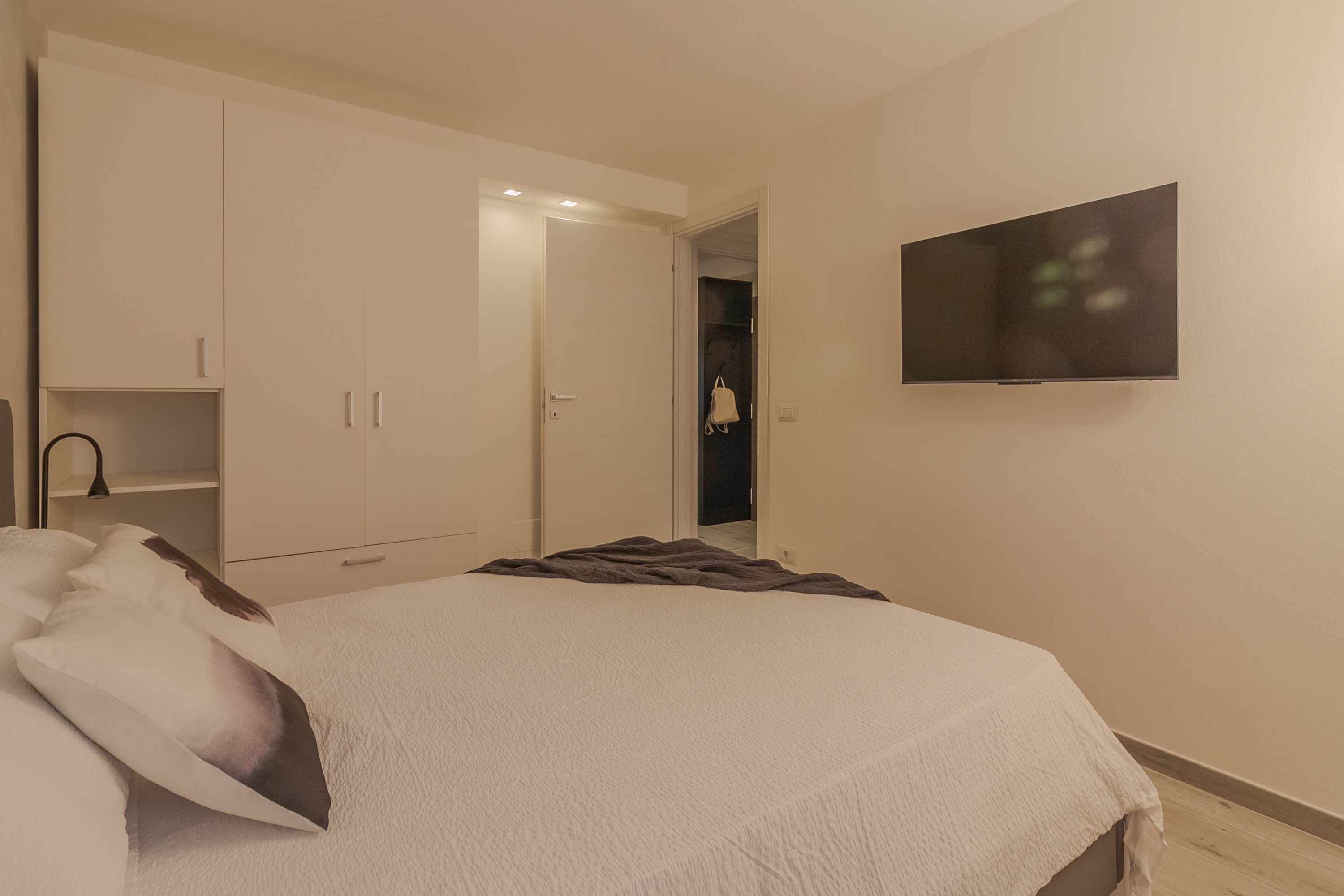 Un dormitorio con una cama, un armario, un televisor y un ropero.