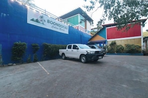 Un pick-up bianco parcheggiato in un parcheggio con un muro blu e un cartello con la scritta 'BOONDOCKS'.