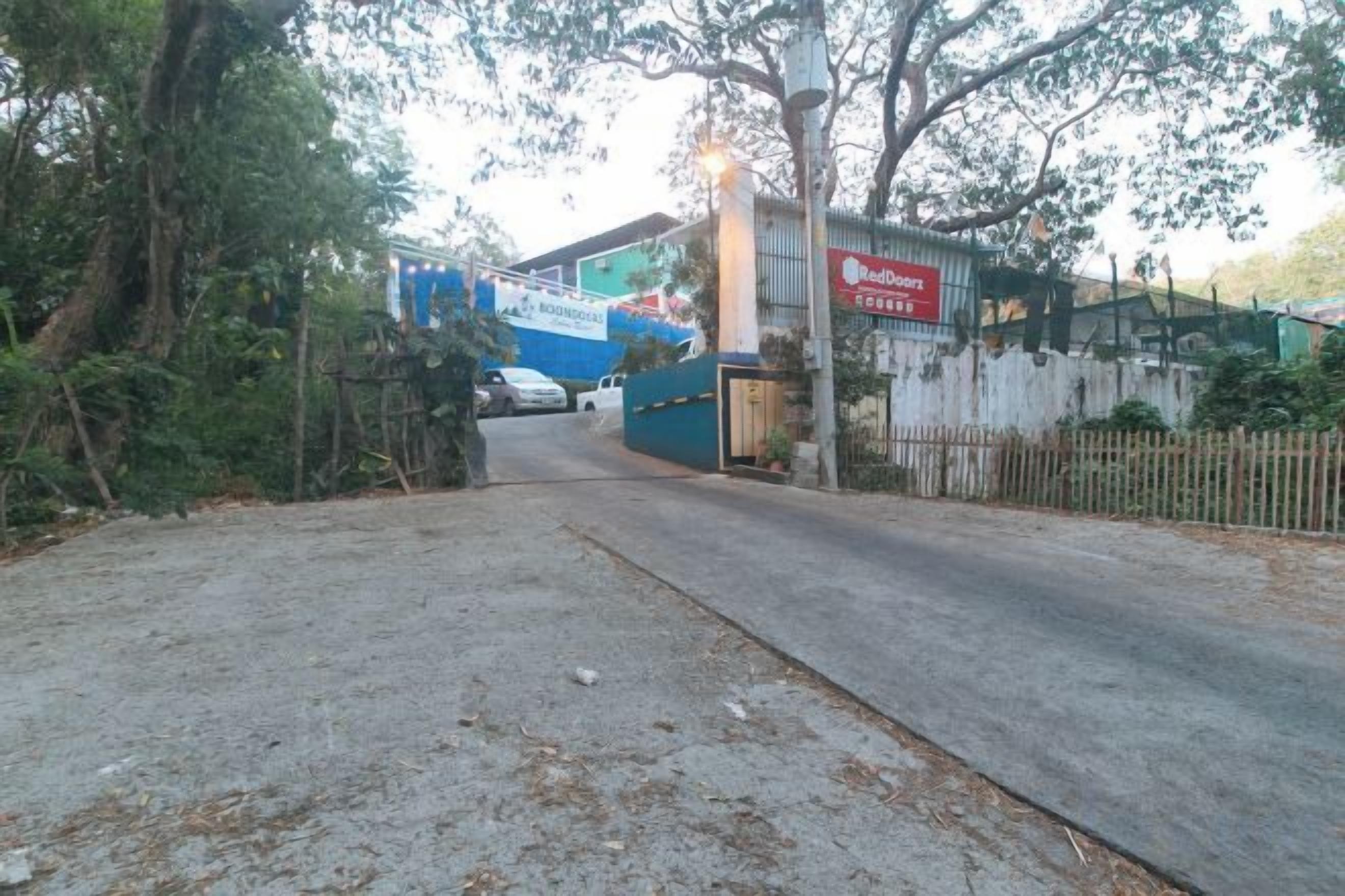 A paved entrance to a property with a blue building and a sign that reads 'Hotel'.