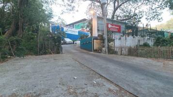 A paved entrance to a property with a blue building and a sign that reads 'Hotel'.