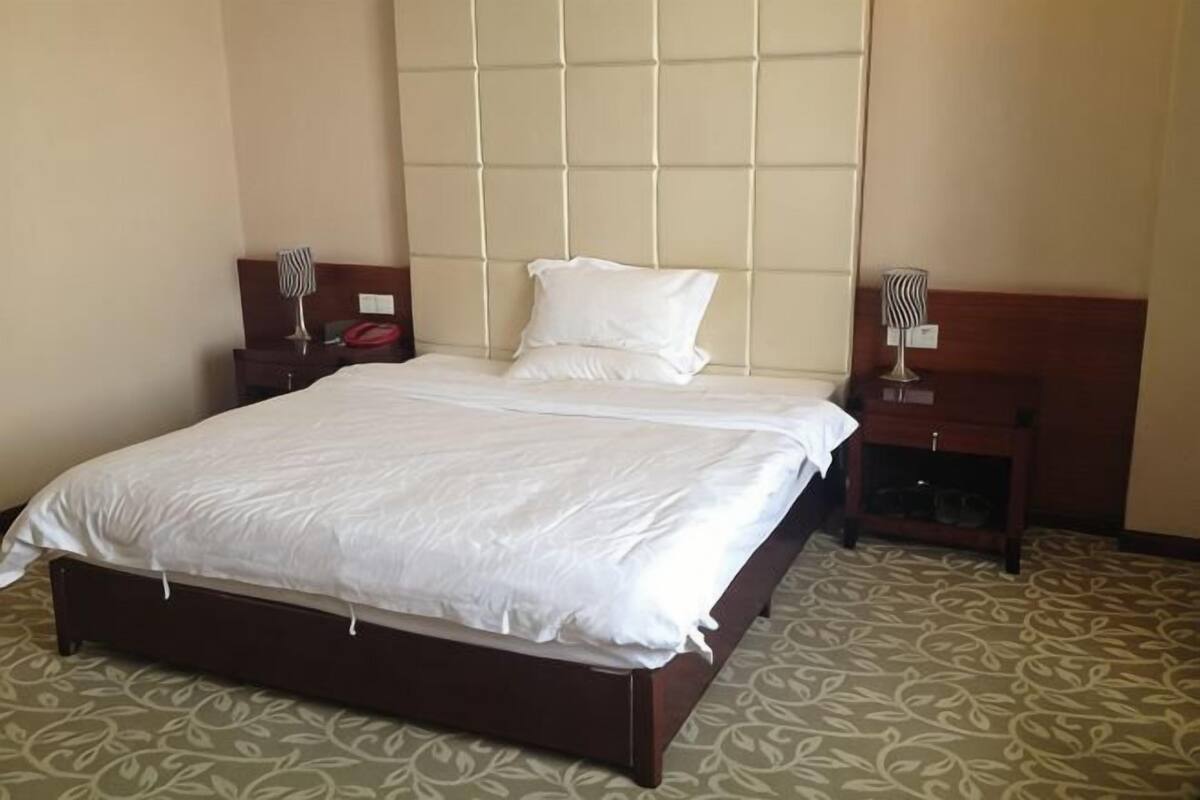 A hotel room with a large bed, two bedside tables, and a headboard with a light fixture.