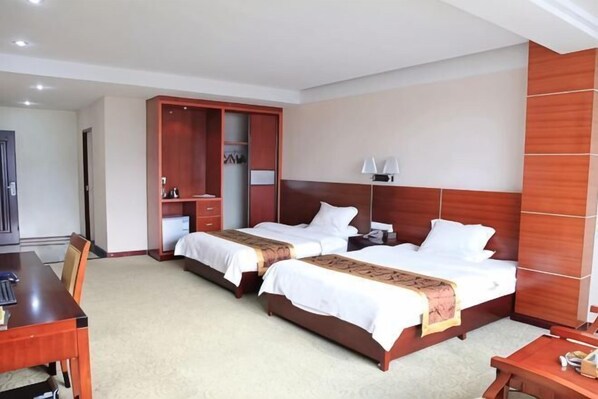 A hotel room with two beds, a desk, and a wardrobe.