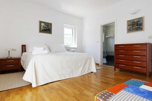 Comfortable bedroom with a large bed, wooden dresser, and bedside table, perfect for a restful stay.