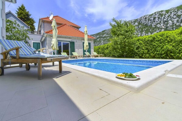 Relax by the pool surrounded by a patio area with lounge chairs and refreshments.