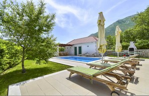 Relax by the pool surrounded by lush greenery and a mountain view.
