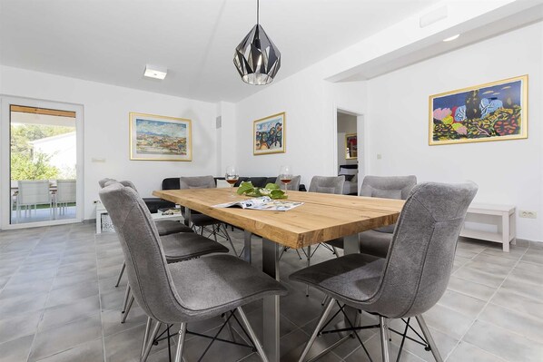 A modern dining room with a wooden table, grey upholstered chairs, and a pendant light.