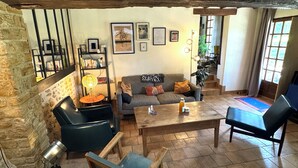 Ein gemütliches Wohnzimmer mit Steinwand, Bücherregal, Sofa, Couchtisch und großem Fenster.