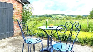 Eine Terrasse mit Tisch und Stühlen, einer Weinflasche und einem Glas Orangensaft.