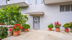 Un edificio con puerta gris, plantas en macetas y un muro de piedra.