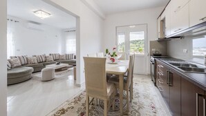 Una cocina moderna con comedor, que incluye un conjunto de sofás, una mesa de comedor con sillas y vistas a través de un ventanal.