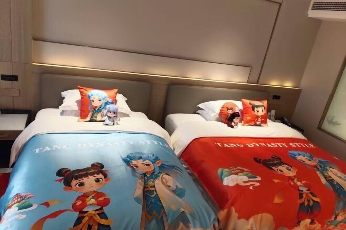 A hotel room with two beds, each with a themed bedspread and pillows featuring animated characters.