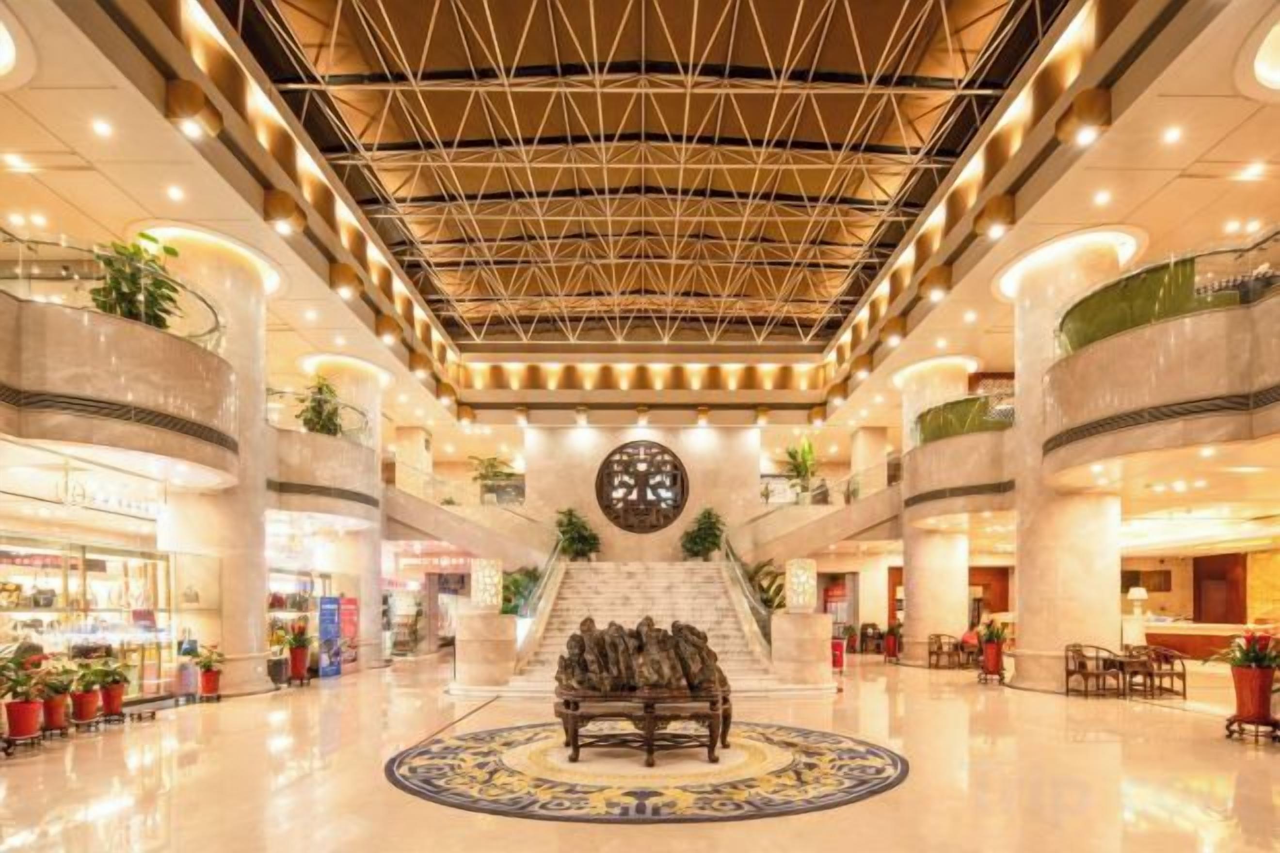 A spacious lobby with a central seating area, a large clock, and multiple levels of balconies.