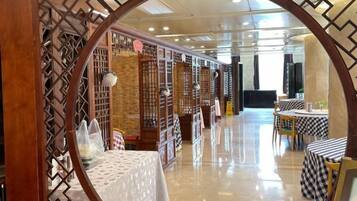 A modern interior with a reflective floor, wooden partitions, and tables with checkered tablecloths.