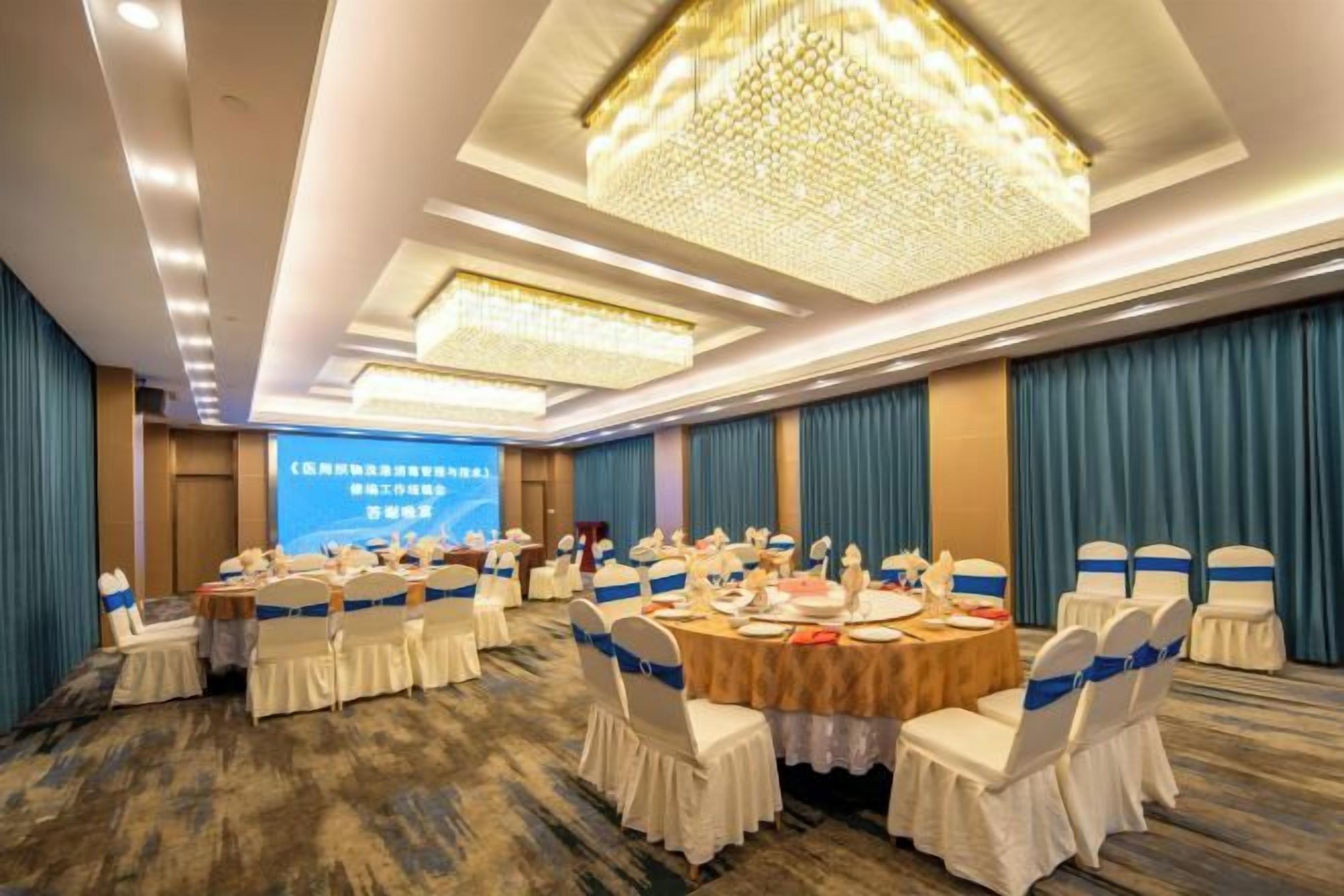 A conference room with round tables, white chairs, and a large screen.