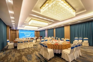 A conference room with round tables, white chairs, and a large screen. - Guomao Hotel (Zhangjiagang)