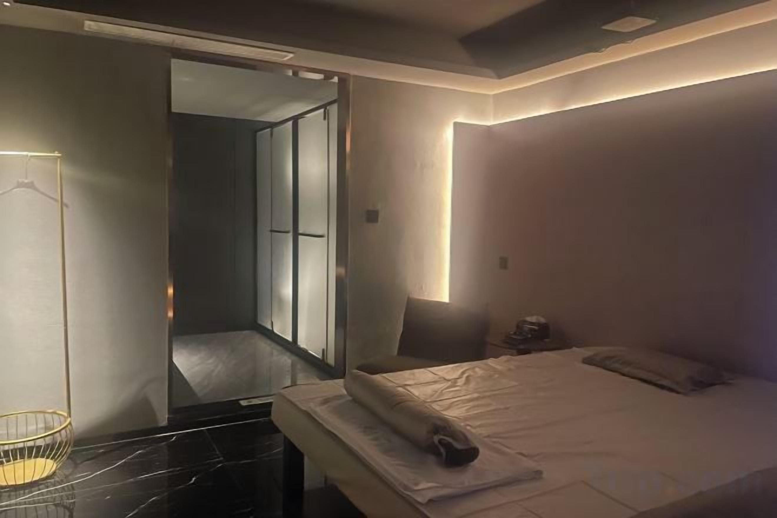 A modern hotel room with a bed, bedside table, and a mirror.