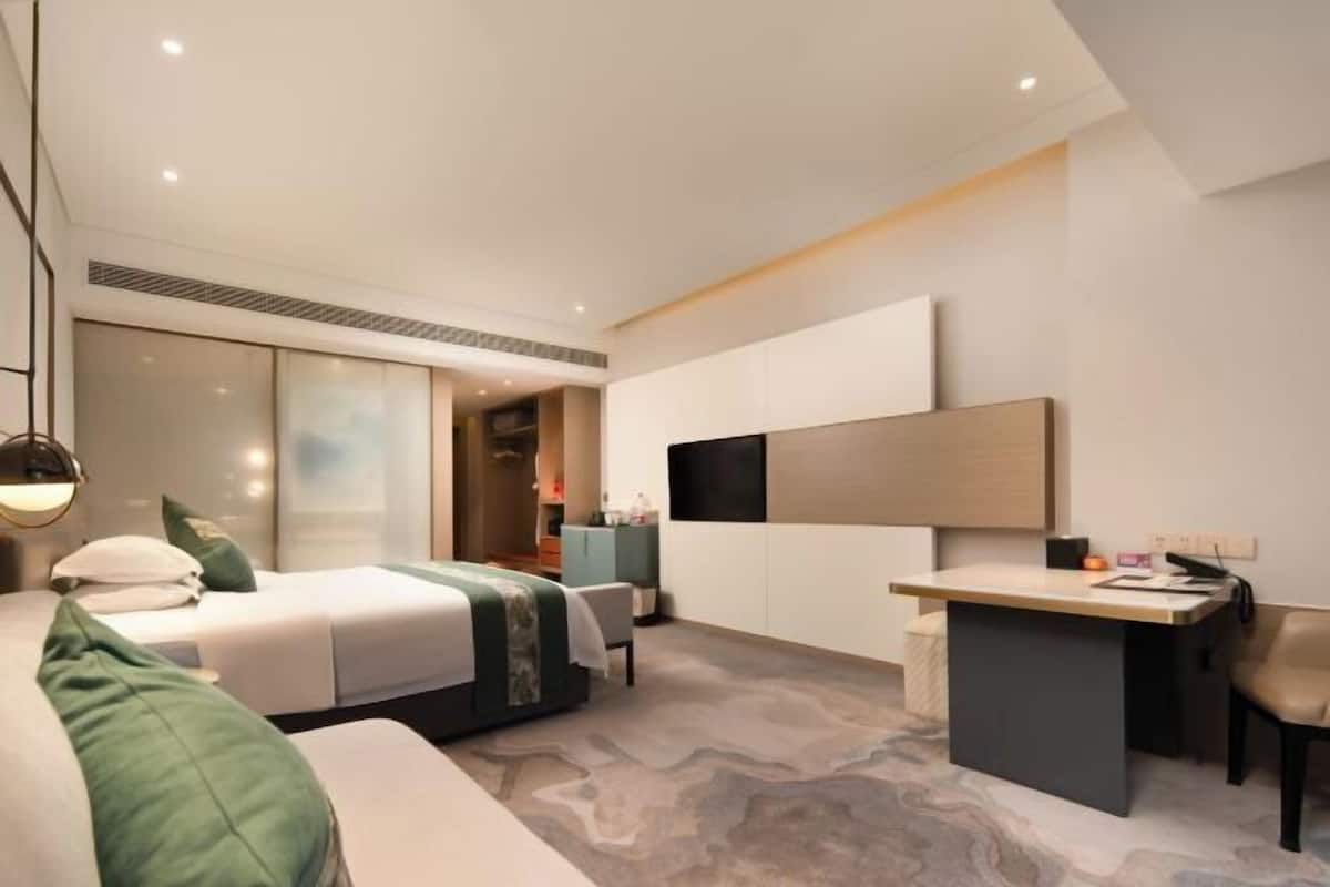 A modern hotel room with a bed, desk, and a large mirror.