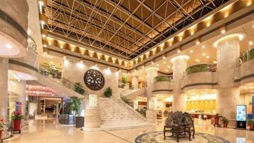 A spacious lobby with a high ceiling, multiple levels, and a central staircase.