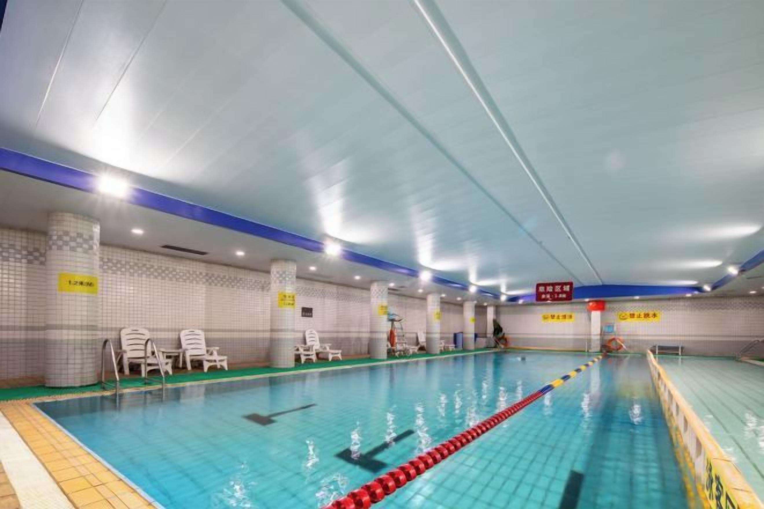 An indoor swimming pool with lane dividers, poolside chairs, and signage.