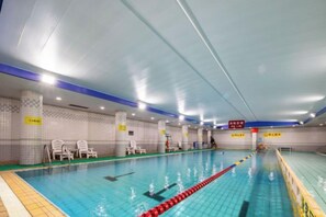 Une piscine intérieure dotée de couloirs délimités, de chaises au bord du bassin et de panneaux d’information.